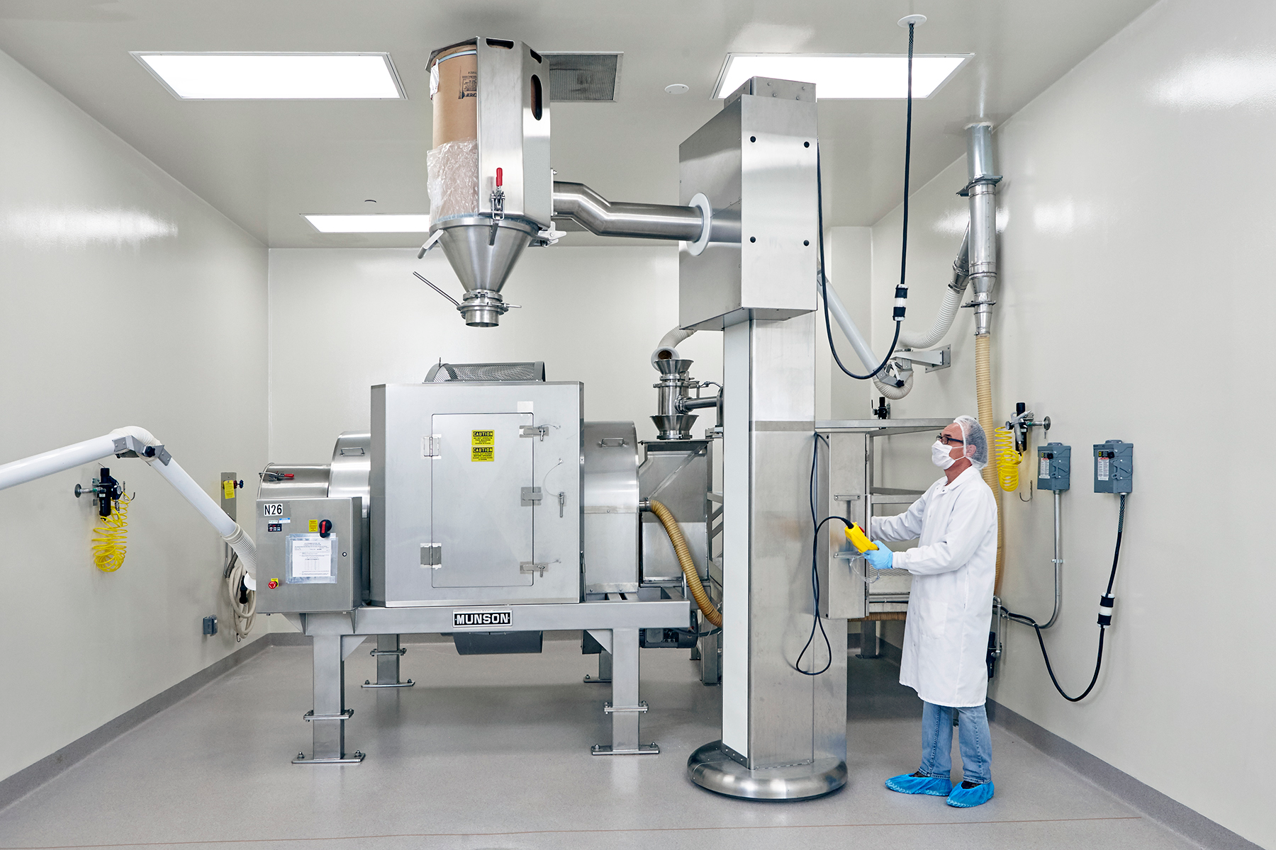 Drums containing each ingredient are lifted, aligned with the mixer's stationary inlet and emptied in a prescribed order according to the master batch record.