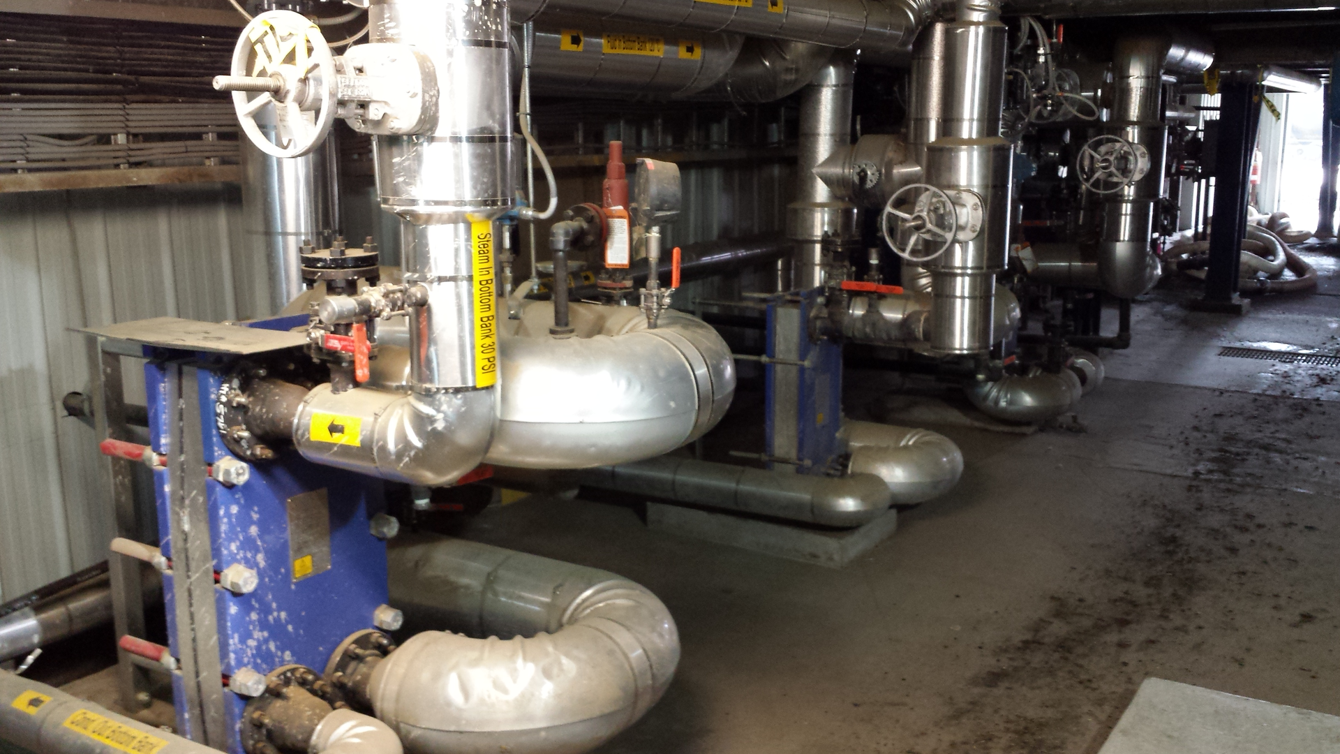 An oilseed installation uses three heat recovery loops to recirculate waste heat through a vertical plate heat exchanger to preheat the seeds.