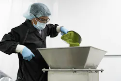 An operator empties a scoop of hand-weighed powder into the mixer intake which remains stationary as the vessel turns. An operator empties a scoop of hand-weighed powder into the mixer intake which remains stationary as the vessel turns.