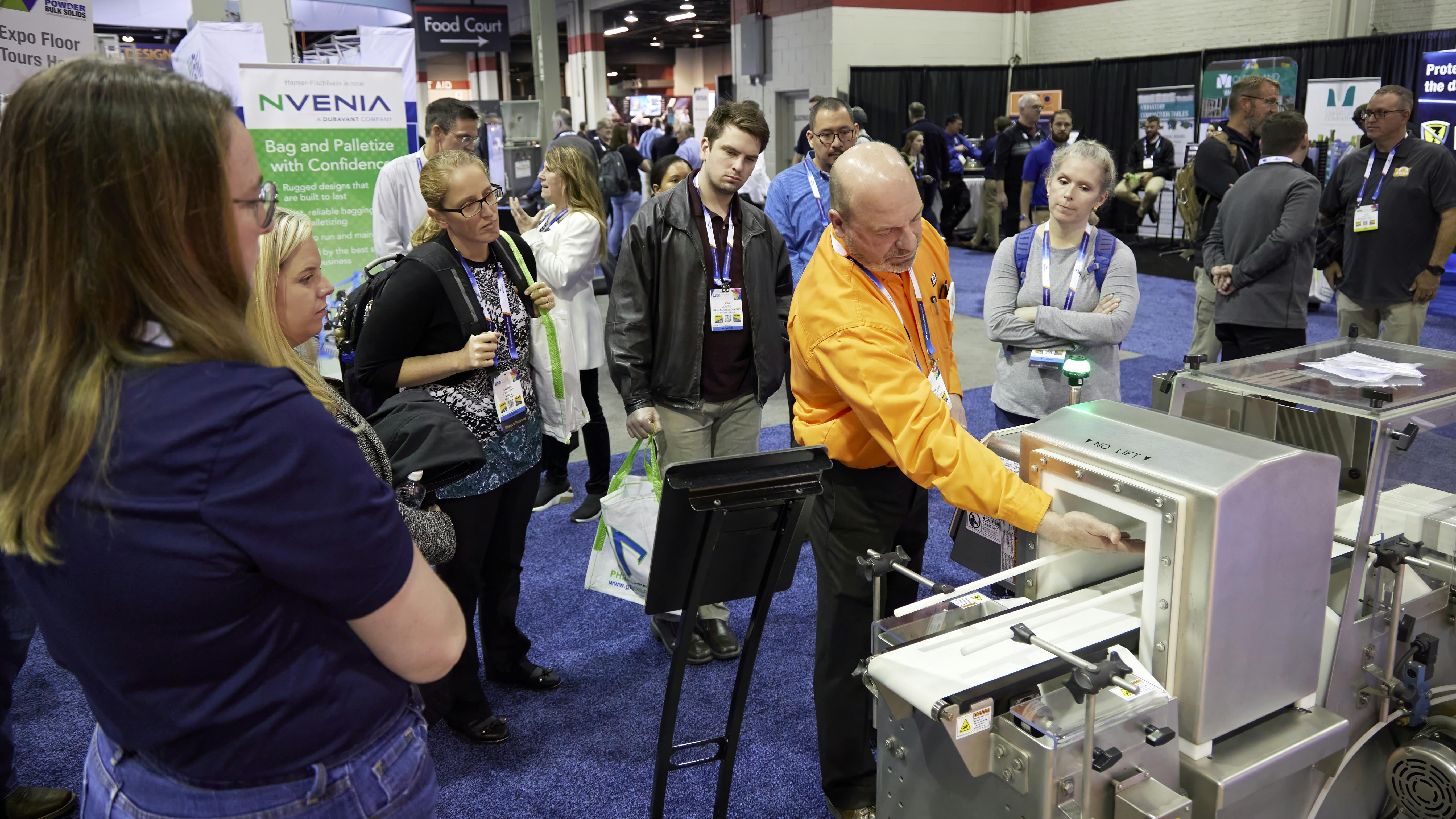 A Powder Show exhibitor demonstrates equipment to attendees on the show floor.
