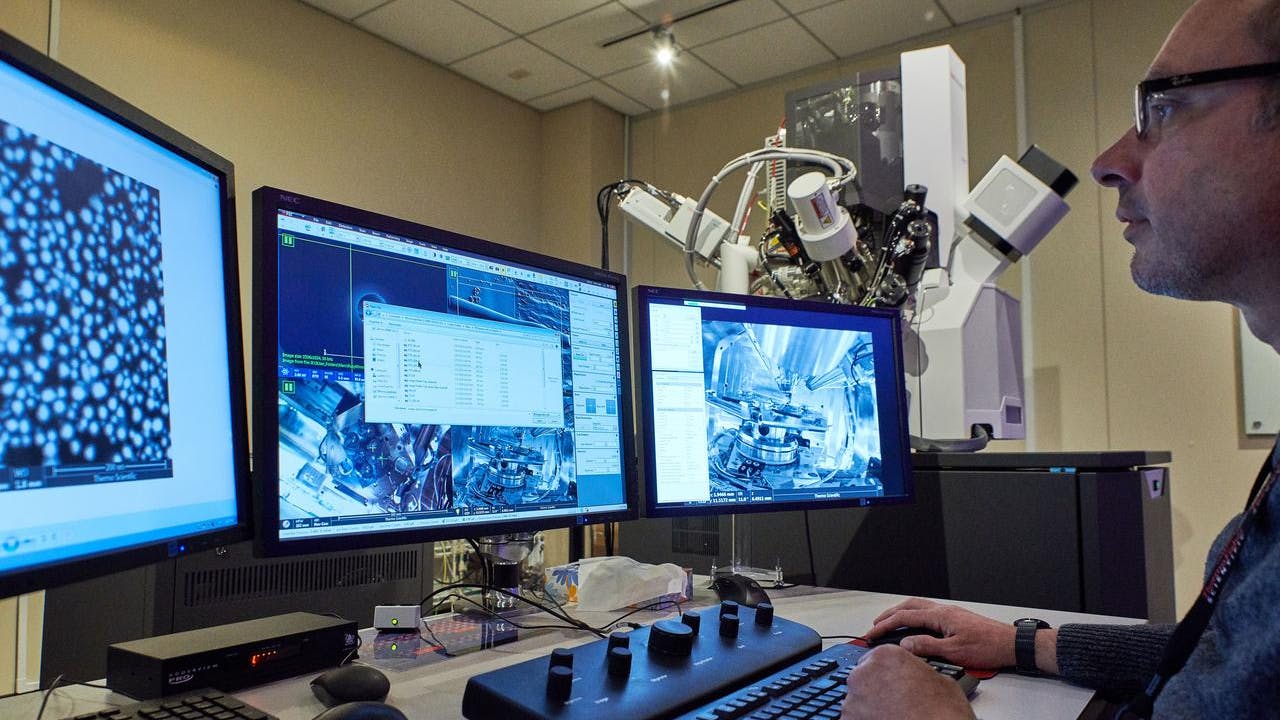 Thermo Fisher Scientific worker at desk reviewing display of three computer screens