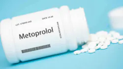 pill bottle labeled Metoprolol, on its side with pills around it, blue background pill bottle labeled Metoprolol, on its side with pills around it, blue background