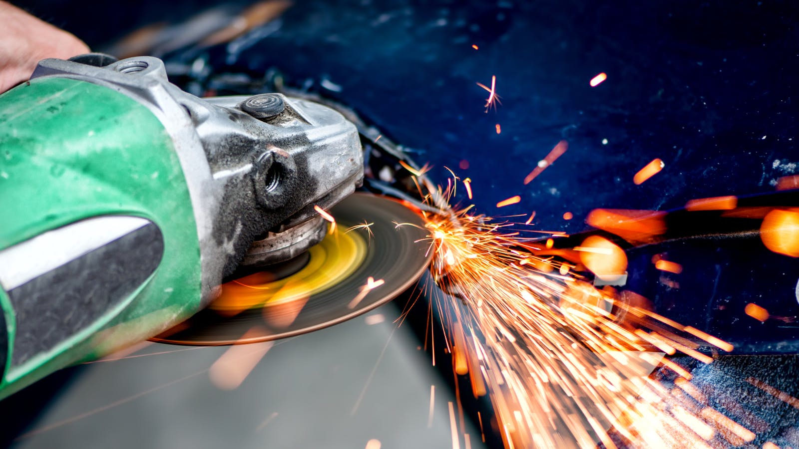 A worker uses an angle grinder, an industrial abrasives product.