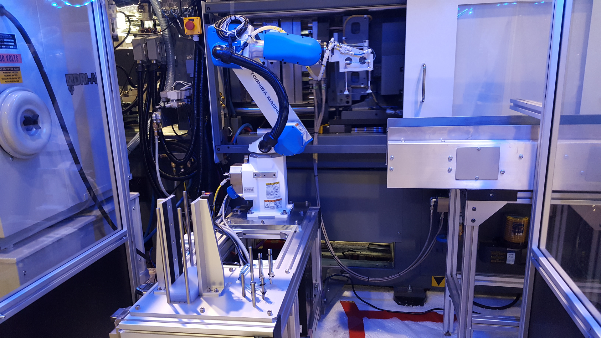 A robot from Shibaura, the company formerly known as Toshiba, operates at an injection molding machine.
