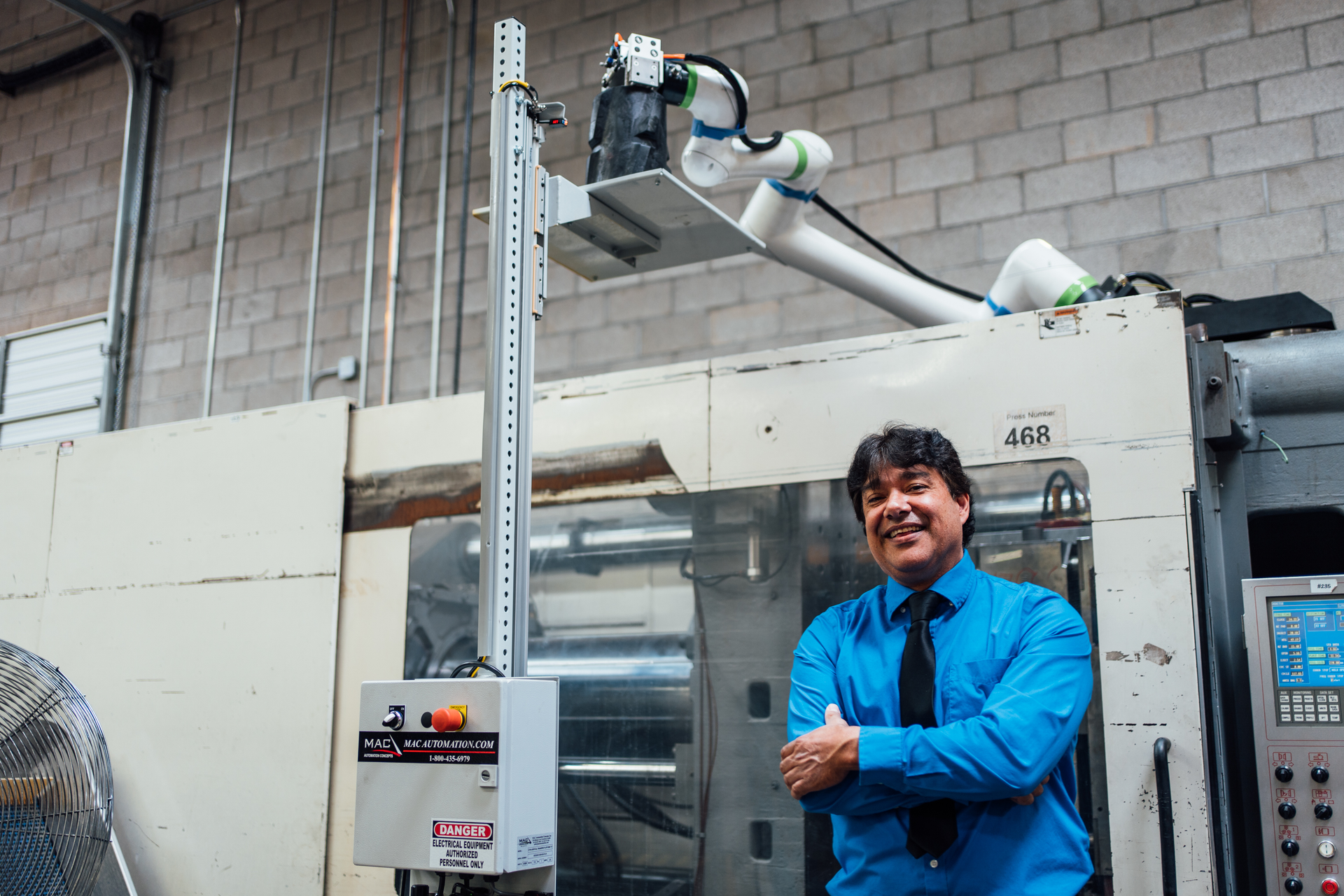 Jeff Galindo, Icon Injection Molding's executive operations specialist, stands next to an injection molding machine equipped with a Fanuc collaborative robot from Formic.