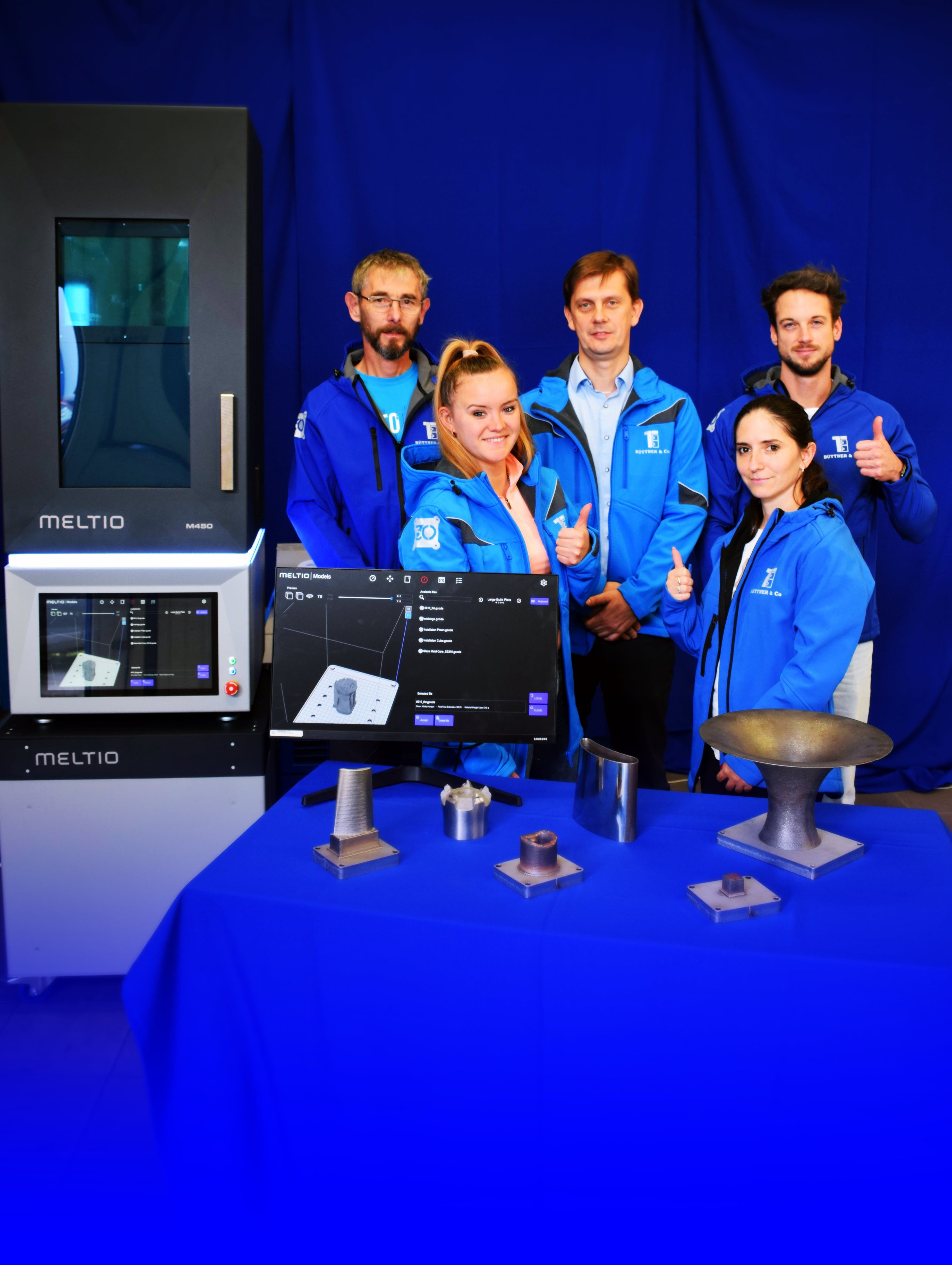 Meltio, the Linares, Spain-based manufacturer of wirelaser metal deposition 3D printers, announced it has named B&uuml;ttner Ltd. its first official sales partner in Hungary. The B&uuml;ttner additive manufacturing team in Hungary stands with samples of parts created by a Meltio printer.