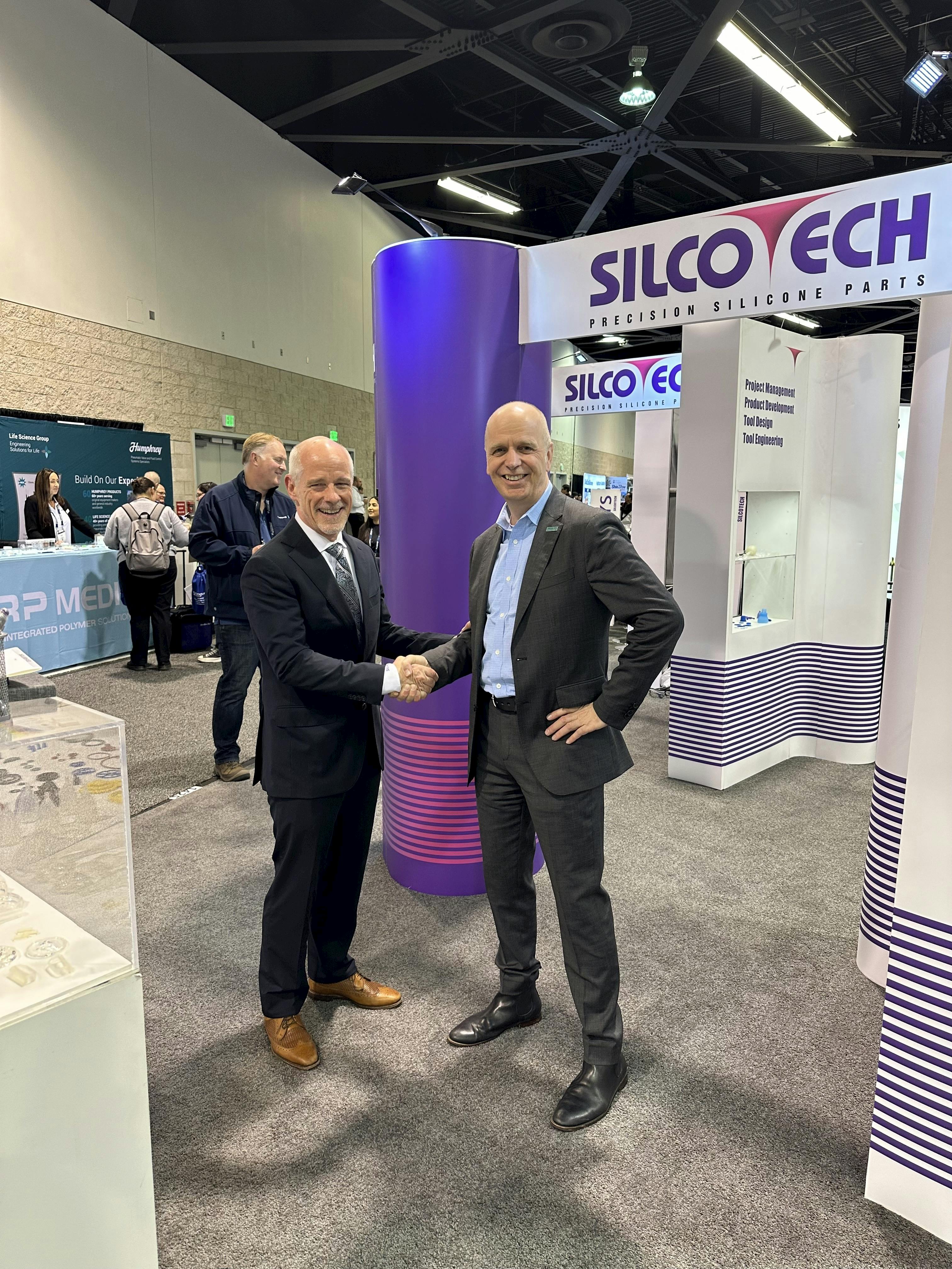 Silcotech President Michael Maloney, left, and Arburg President Martin Baumann, right, shake hands at Silcotech's booth.