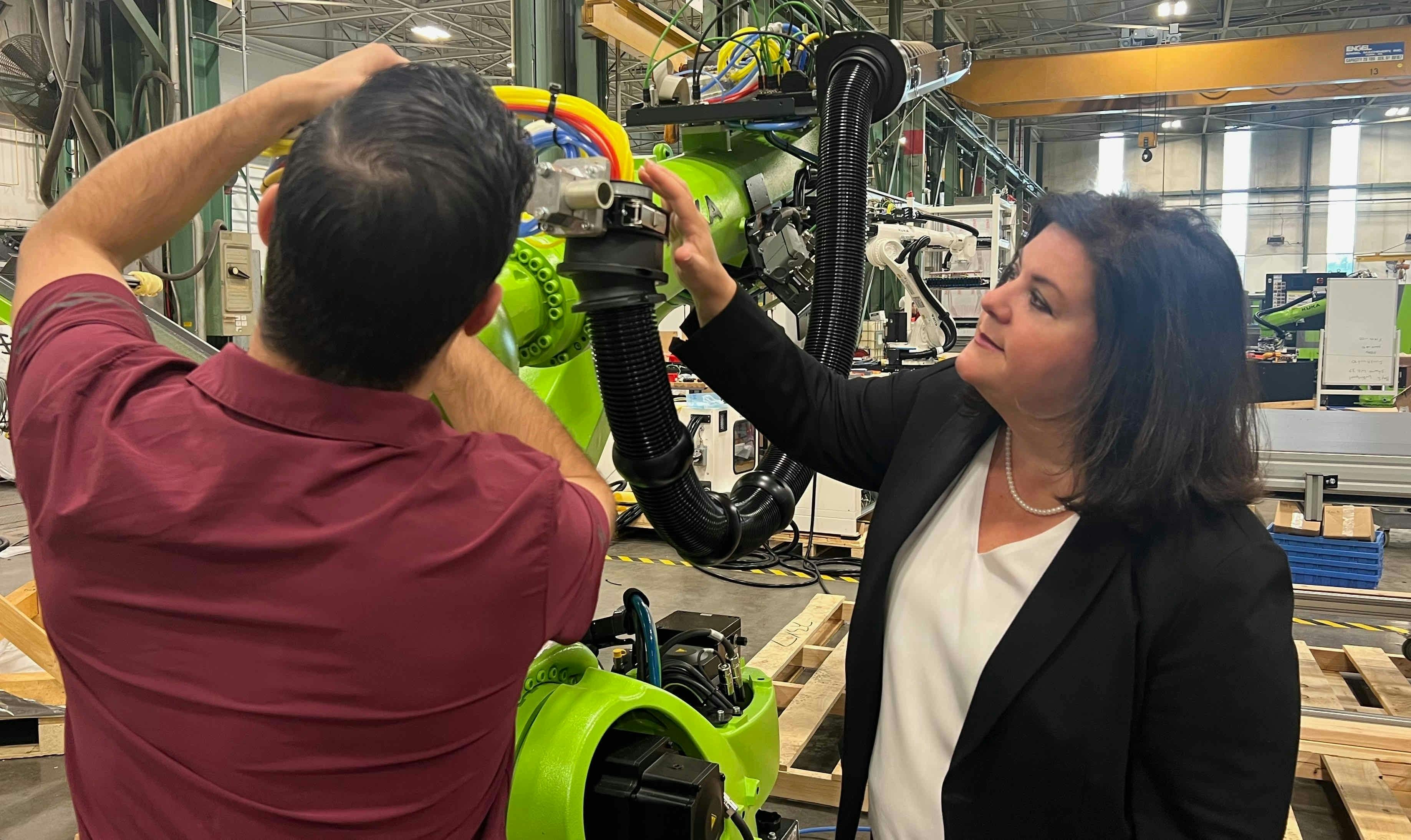 Vanessa Malena, president of Engel North America, watches a technician make adjustments to the end-of-arm-tool on an Engel robot arm.