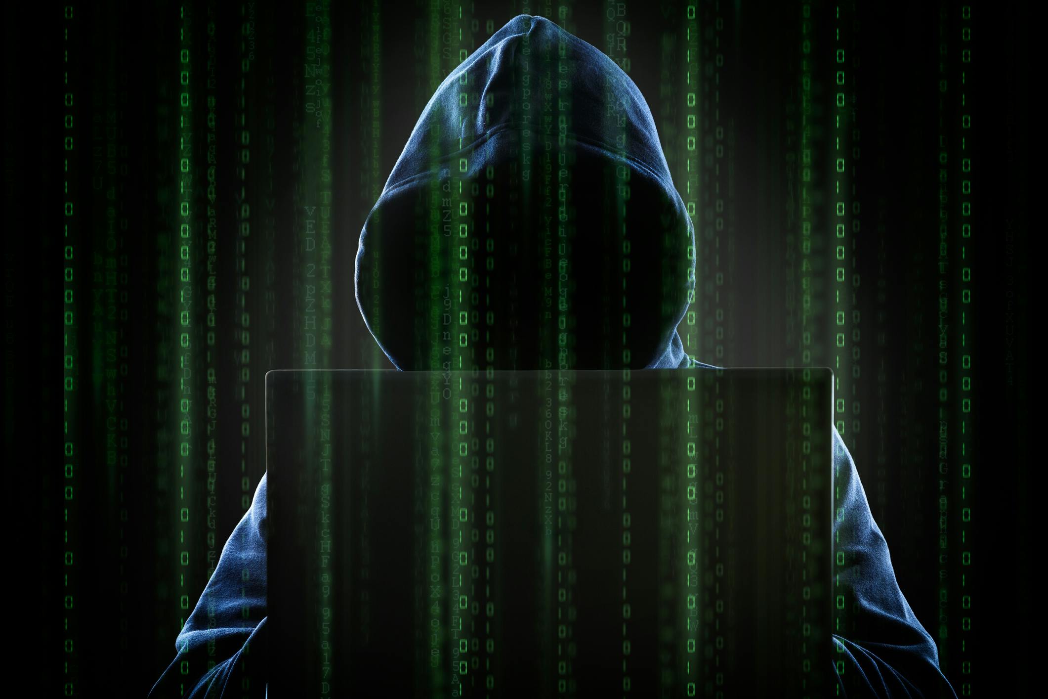 A hooded hacker at a computer.