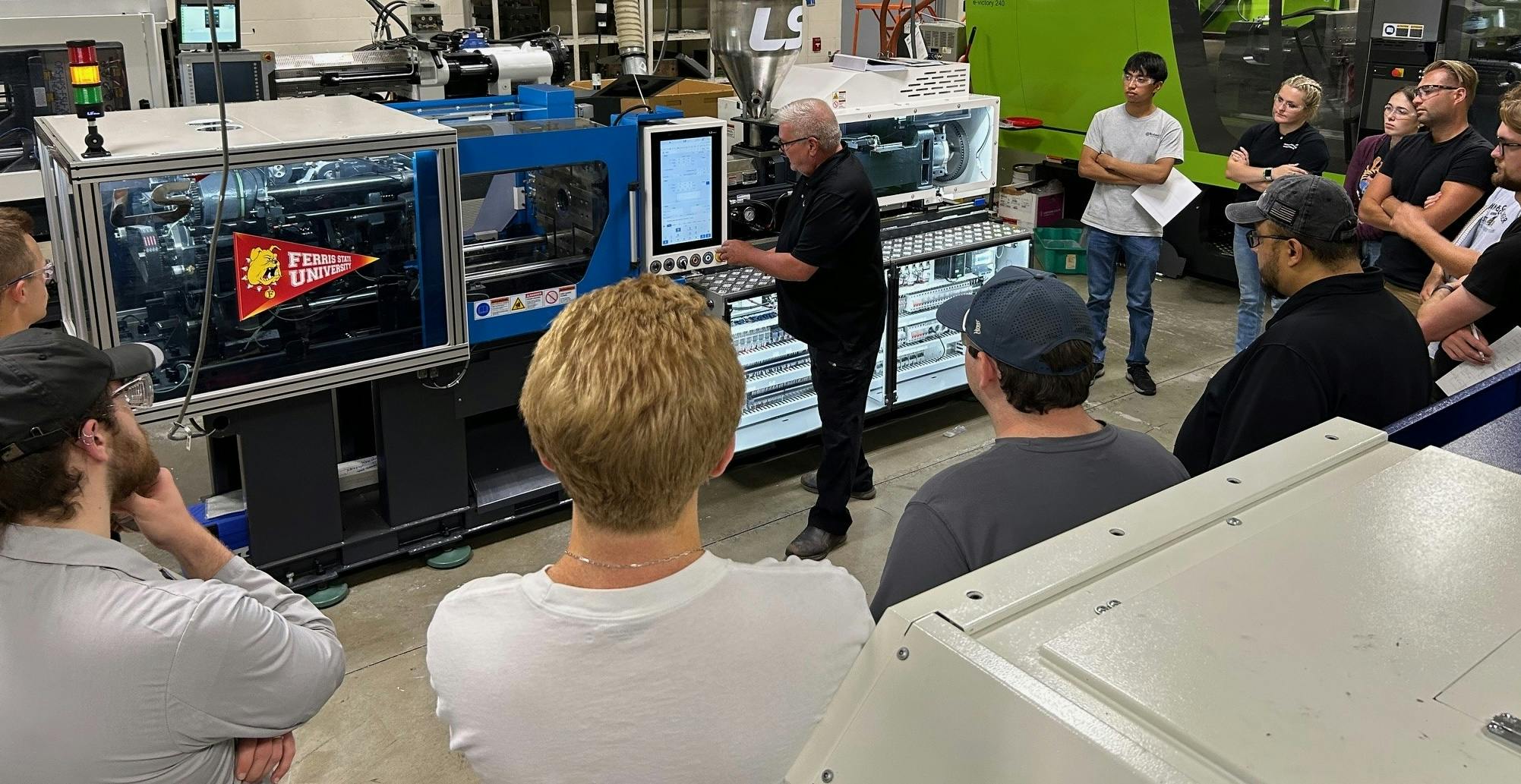 John Wiley, director of customer service for LS Mtron, tells the advanced injection molding class at Ferris State University about the consigned One 55E injection molding machine they will be using.