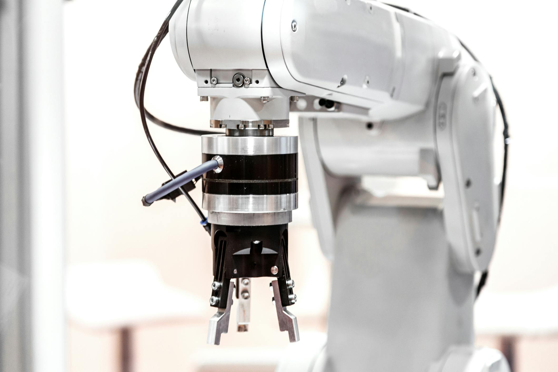A white industrial robot arm with a gripper end-of-arm tool