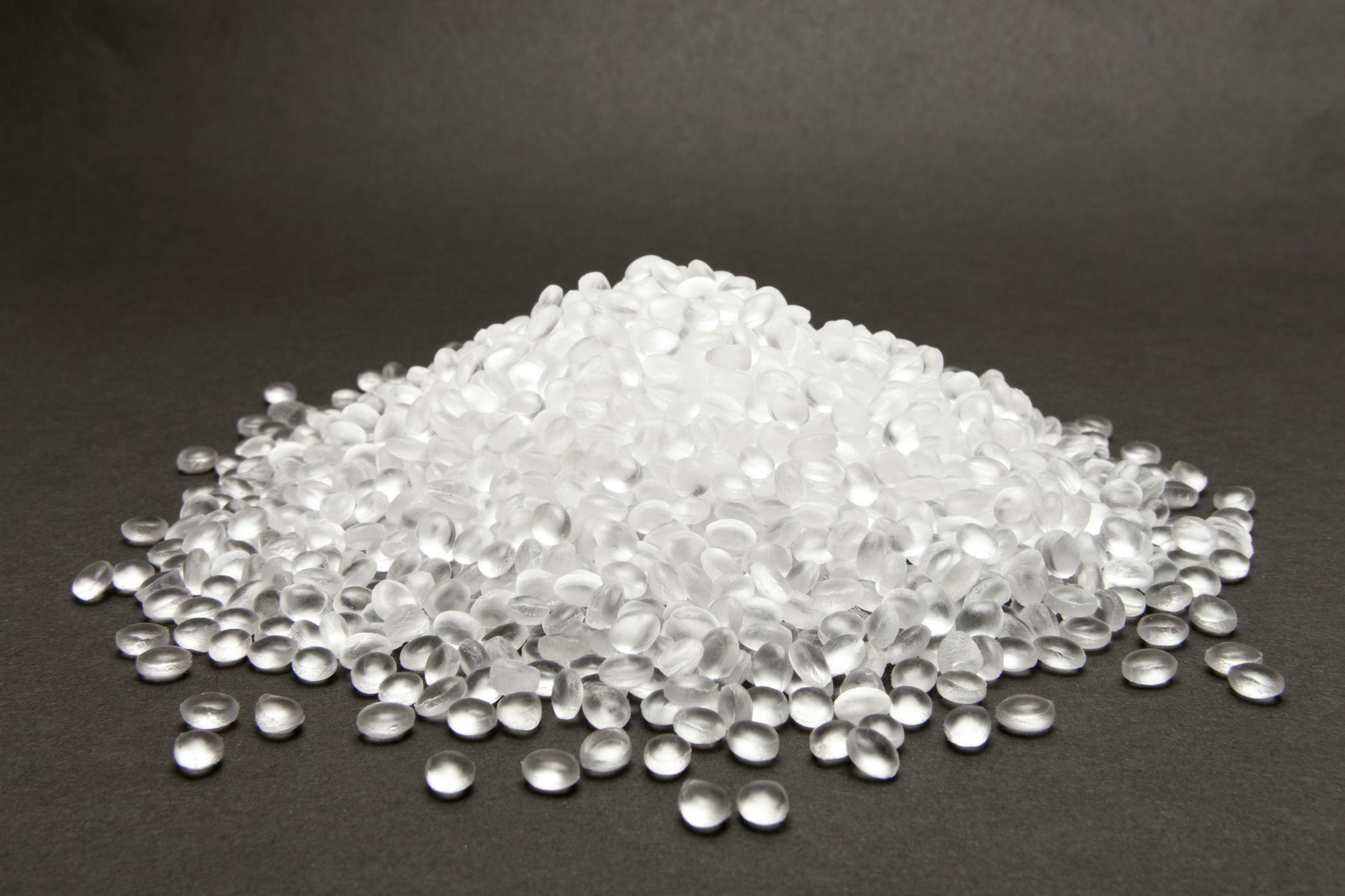 Clear high density polyethylene resin pellets on gray background