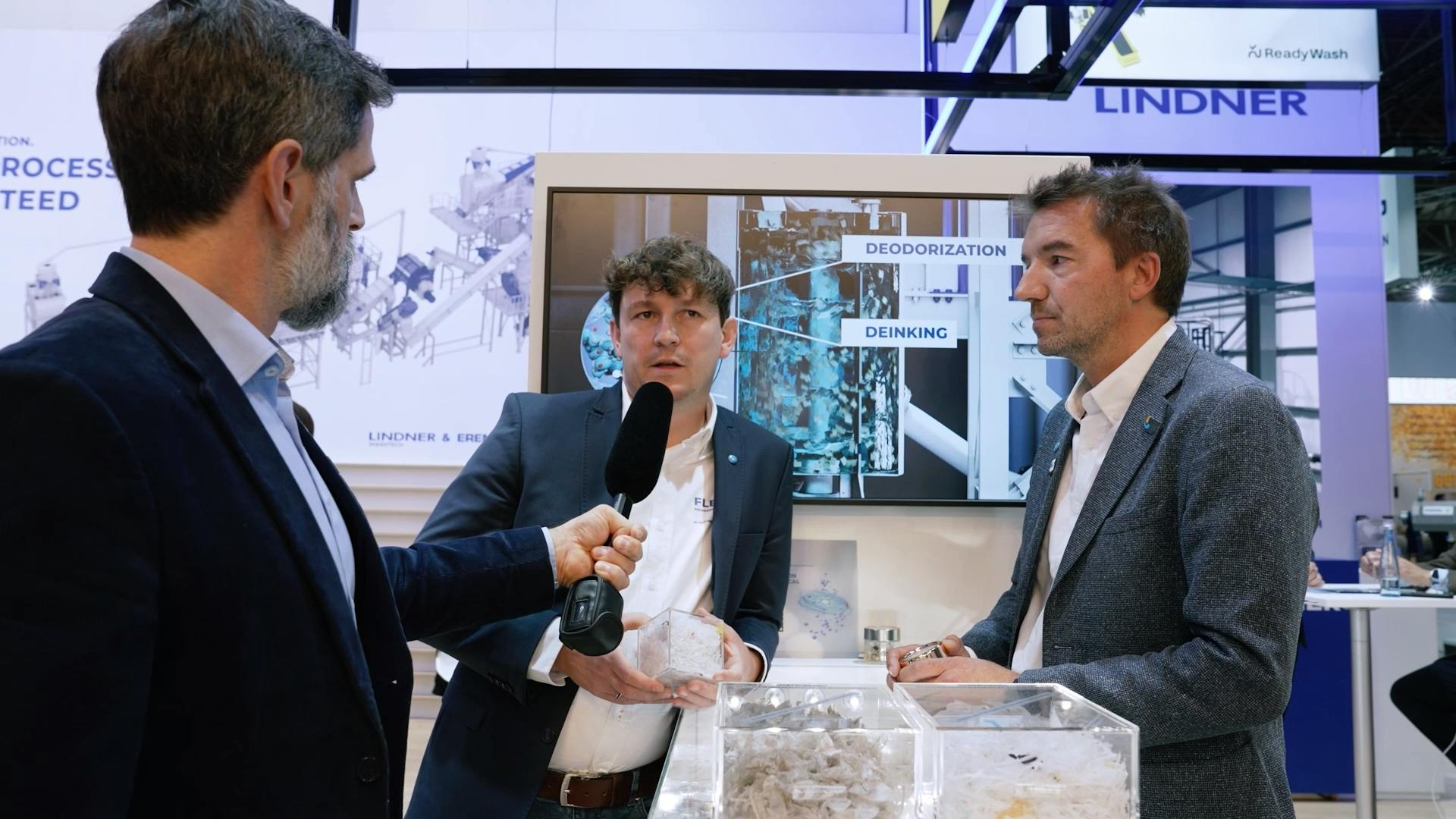 Yannick Stanau, business development manager for Lindner Washtech (center) and Gian De Belder, technical director, packaging sustainability at P&G (right) are interviewed at K 2025.