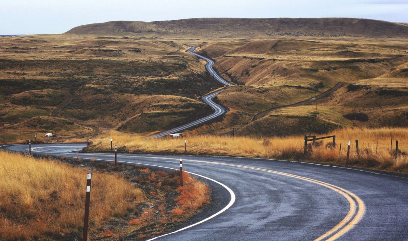 66fdb9cdde5fd13c2c547eae Pavedroadwindingthroughbrowngrasshillsoffintodista