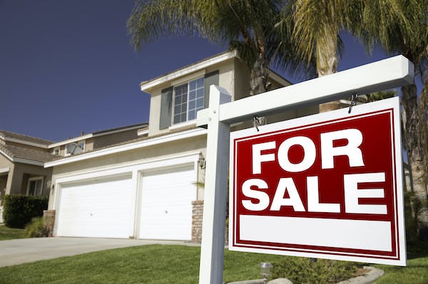 Single-family home with a 'for sale' sign in the front yard