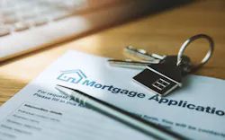 A mortgage application sits on a desk with a pen and a house key on top of it A mortgage application sits on a desk with a pen and a house key on top of it