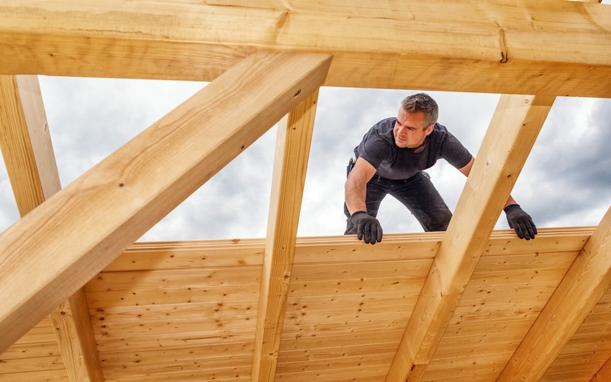 A builder works on the roof of a building