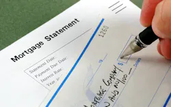 A closeup image of a hand writing out a check to a mortgage company A closeup image of a hand writing out a check to a mortgage company
