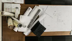 rolls of floor plans on wood desk with laptop rolls of floor plans on wood desk with laptop