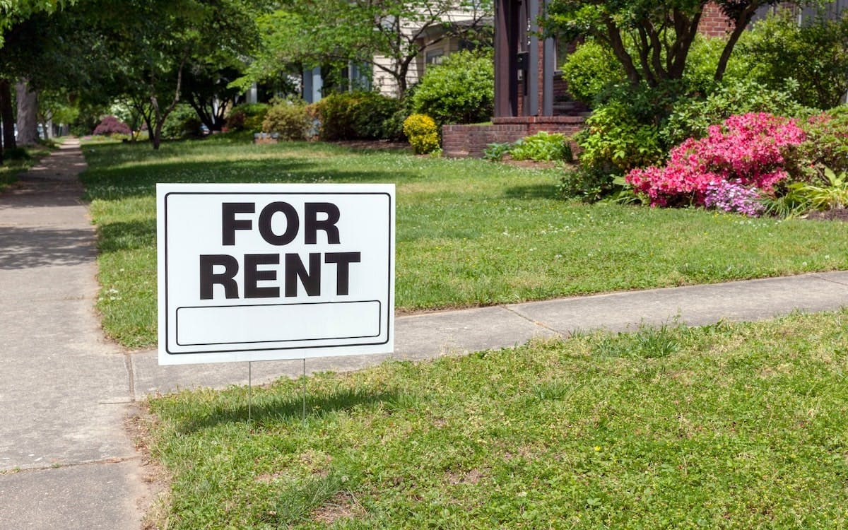 A 'For Rent' sign posted in a front yard