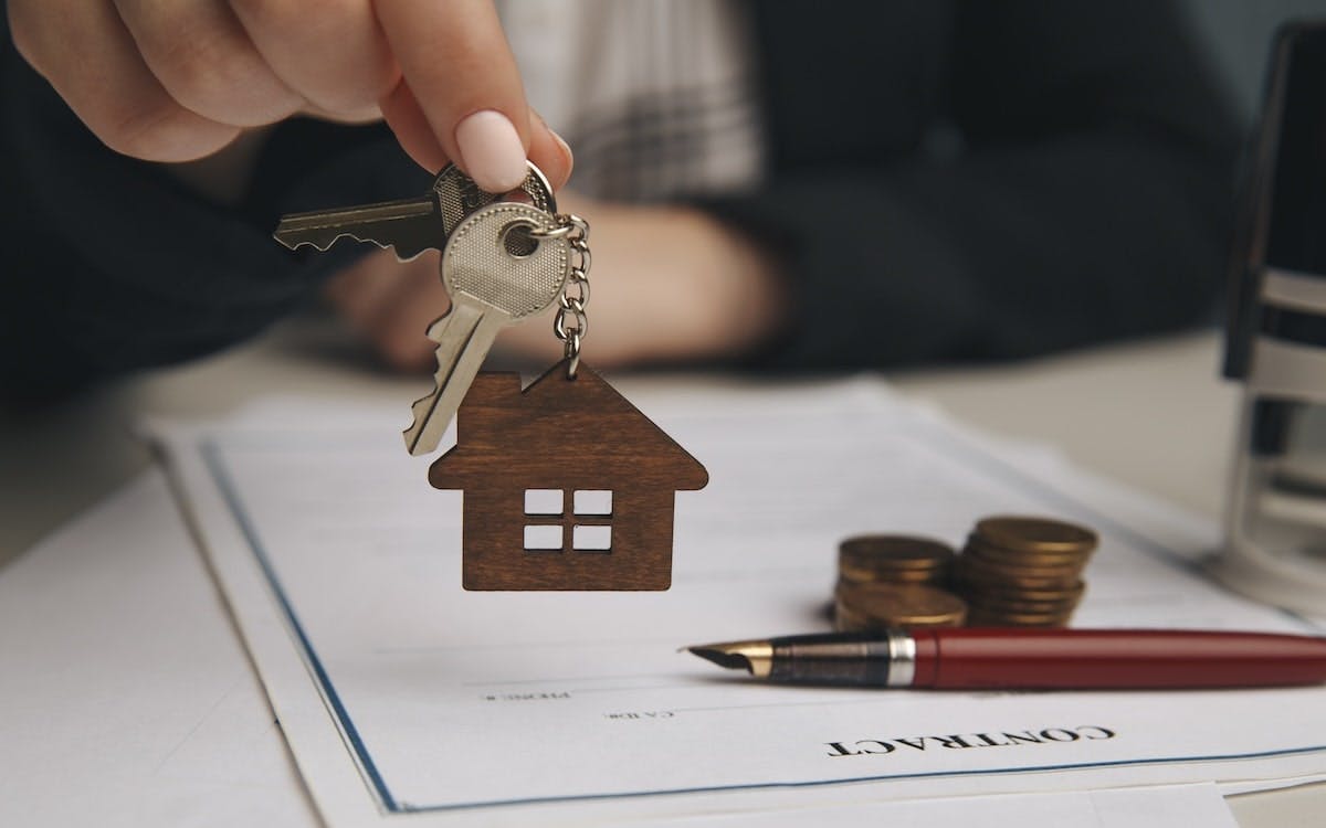 A hand holds up a key above a mortgage loan contract