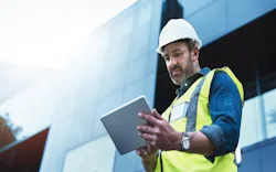 A construction worker uses a software program on a tablet while working on a jobsite A construction worker uses a software program on a tablet while working on a jobsite