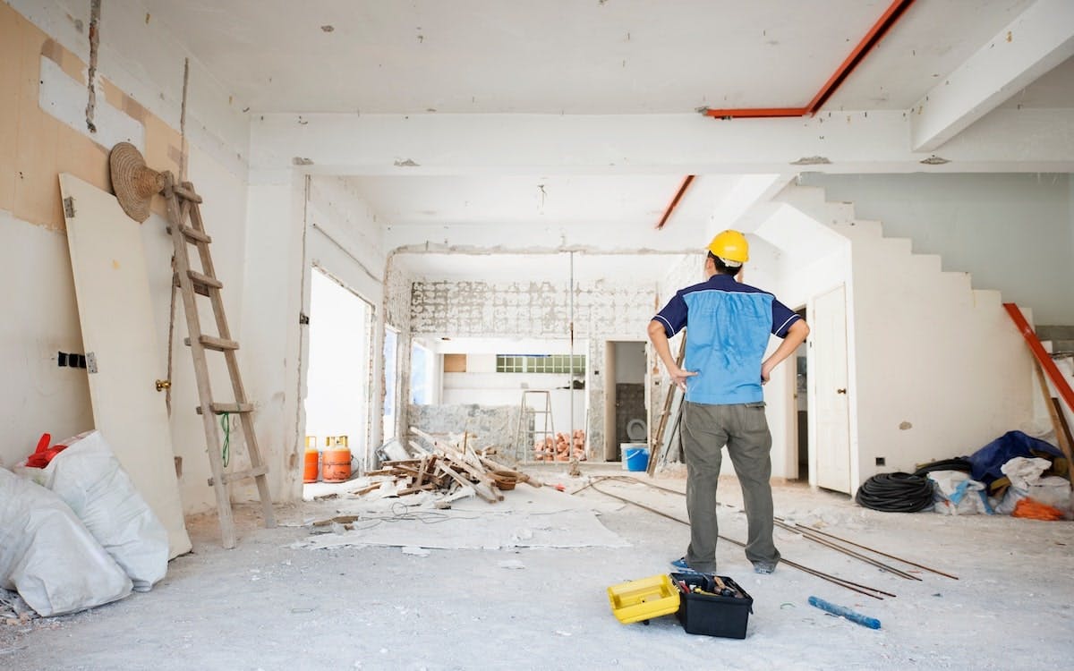 A man in a yellow hard hat looks over home renovation work