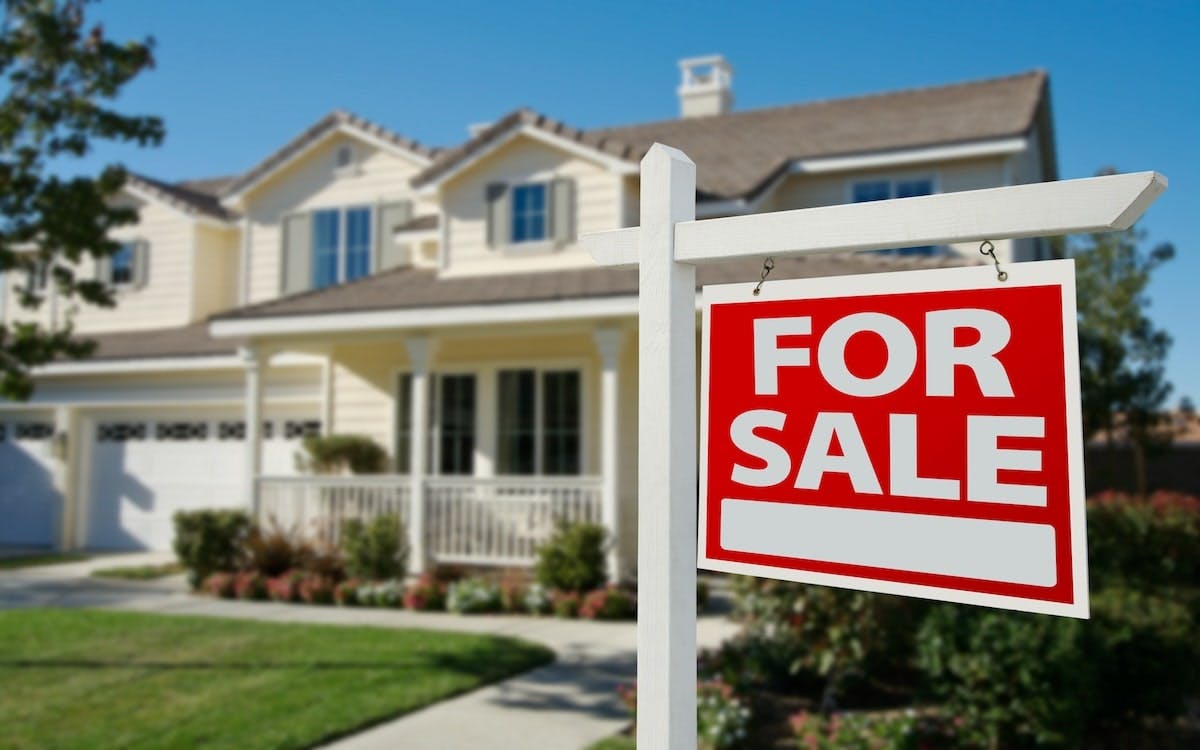 A home with a red 'For Sale' sign in the front yard