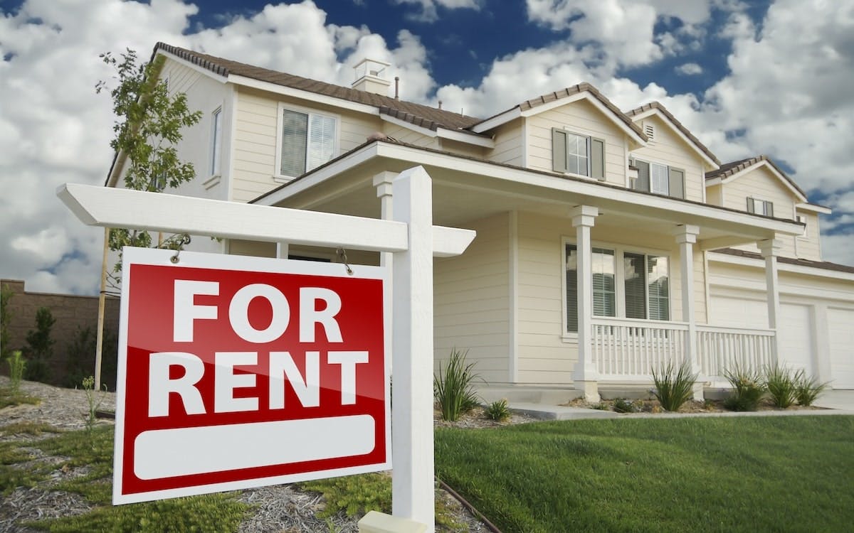 A single-family home that has a red 'For Rent' sign in the front yard