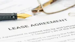 A close-up of a lease agreement with a pair of glasses and a pen sitting on top of them. A close-up of a lease agreement with a pair of glasses and a pen sitting on top of them.