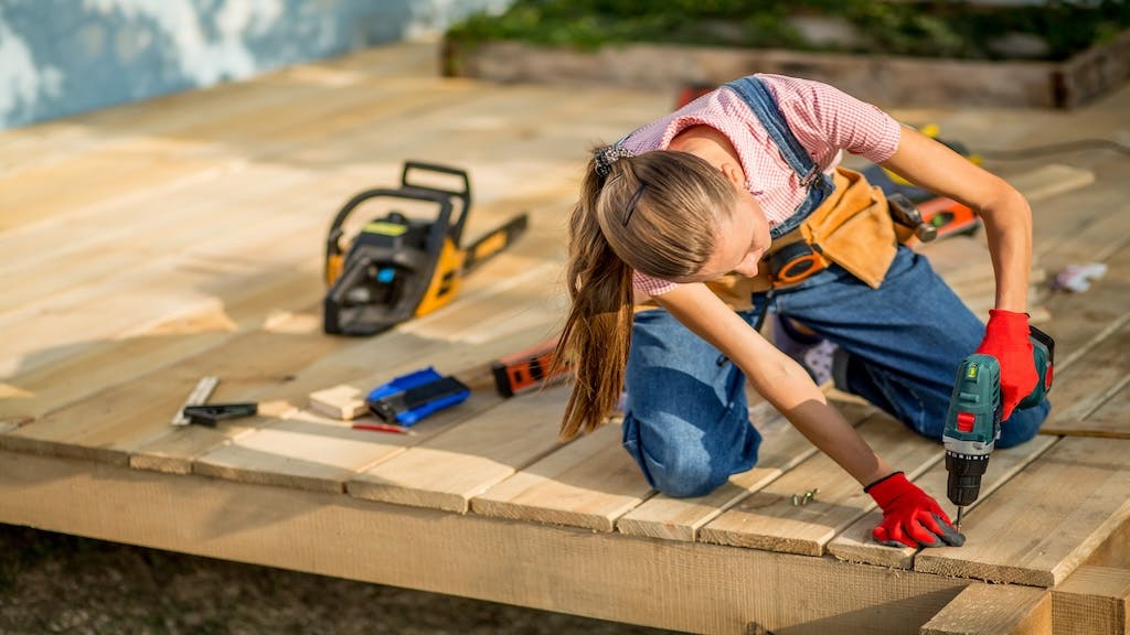 A woman carpenter works on a home decking project.
