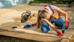 A woman carpenter works on a home decking project. A woman carpenter works on a home decking project.