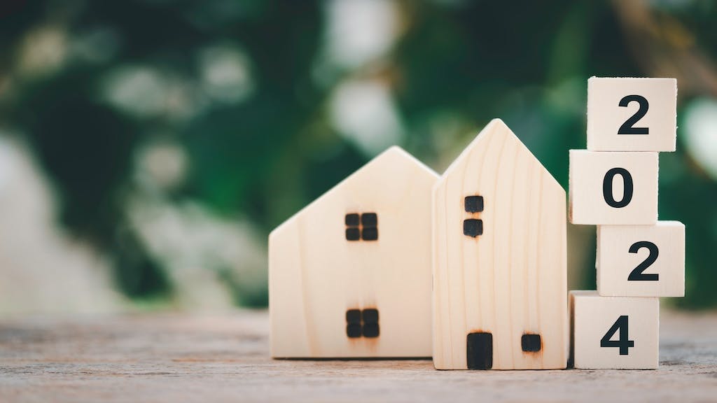 A wooden model home with blocks spelling out '2024' displayed next to it