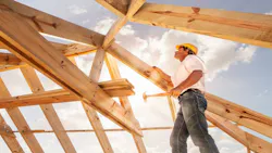 A roofer works on framing the roof of a home. A roofer works on framing the roof of a home.