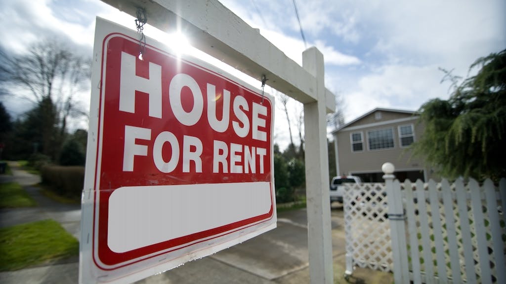 A single-family home with a sign in the front yard that says 'House For Rent'