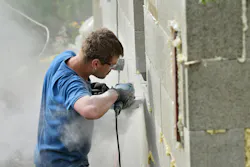 Construction worker without a face mask cuts concrete block, creating clouds of silica dust Construction worker without a face mask cuts concrete block, creating clouds of silica dust