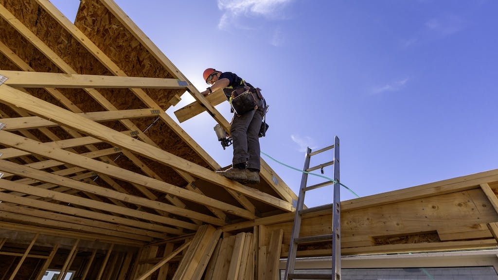 A construction worker frames the roof of a new home as single-family housing inventory sees an increase