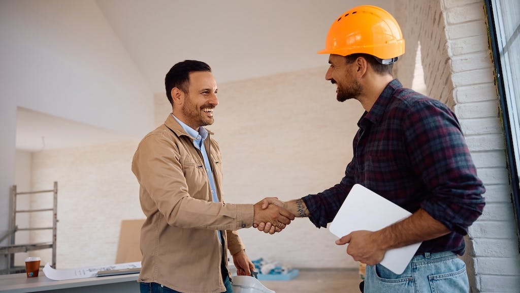 Construction worker shakes hands with a potential employer as the number of new construction job openings declines.