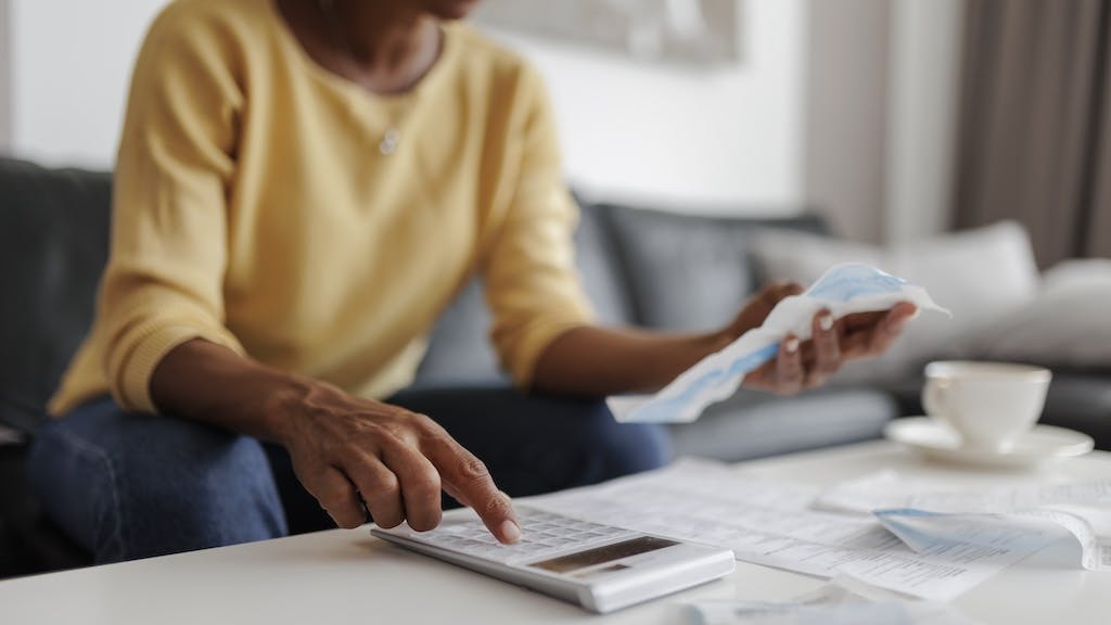 A homeowner goes over her budget on a calculator as homeowner concerns mount about housing affordability.