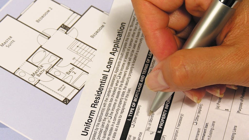 A person filling out a mortgage application as the rate of mortgage applications declines.