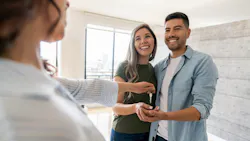 A sales associate makes a home sale and hands the new homeowners their keys. A sales associate makes a home sale and hands the new homeowners their keys.