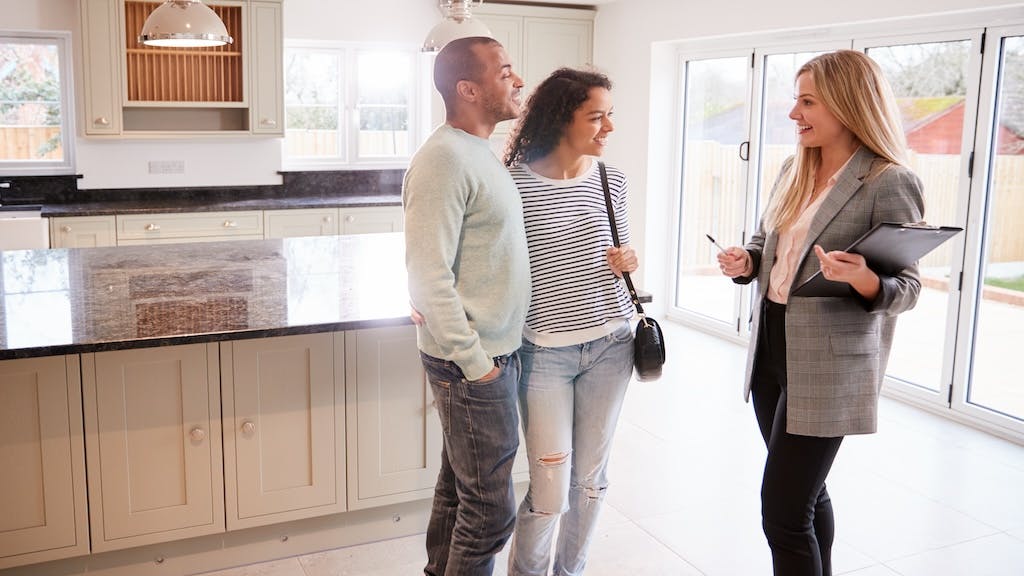 A real estate agent shows prospective homebuyers around a home