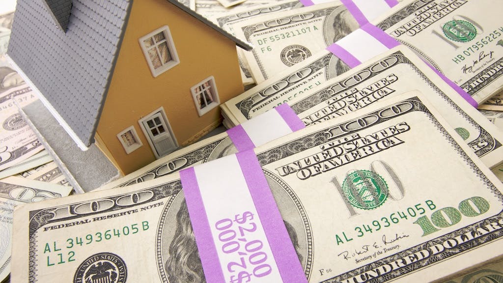 A model home sitting on stacks of money represents home equity