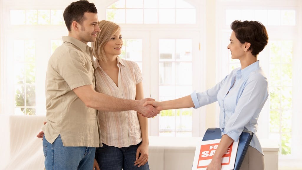A real estate agent shaking hands with a couple after a recent home sale.