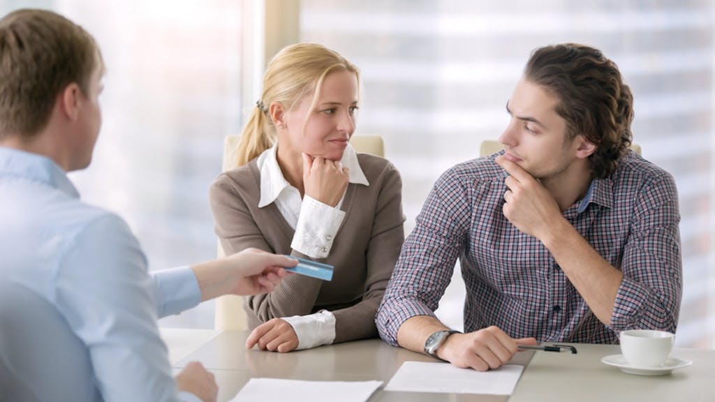 Young couple realizes it is a bad time to buy a home while speaking to a real estate agent