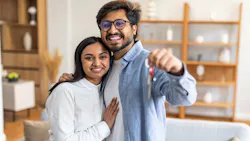 Millennial couple holds up keys to newly purchased home Millennial couple holds up keys to newly purchased home