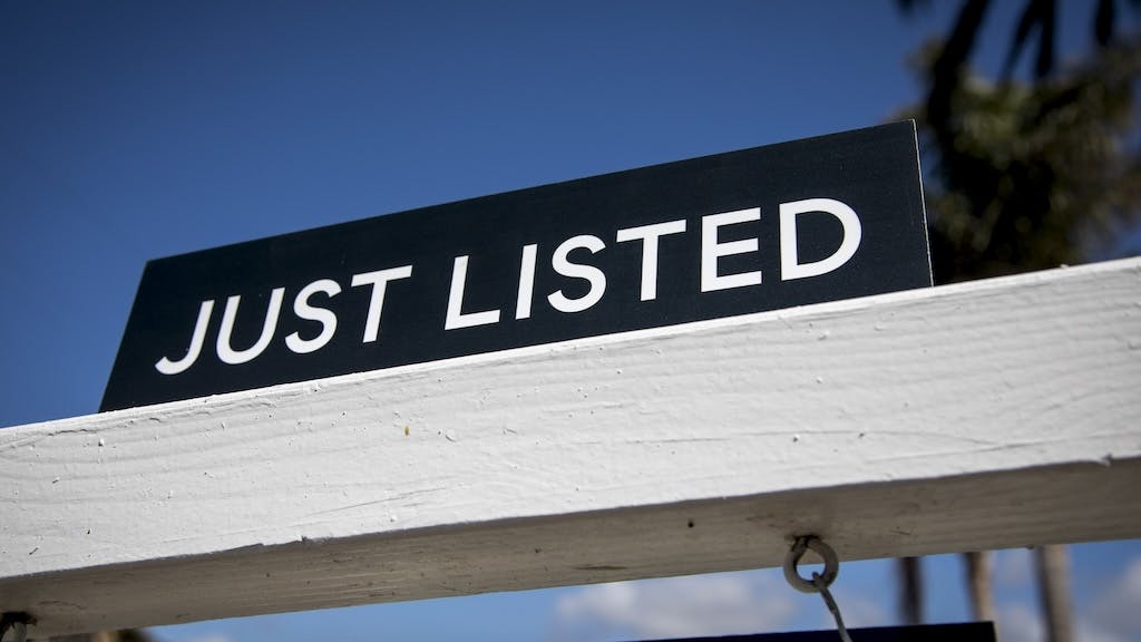 A closeup of a sign that reads 'Just Listed,' indicating that a home was made available for sale