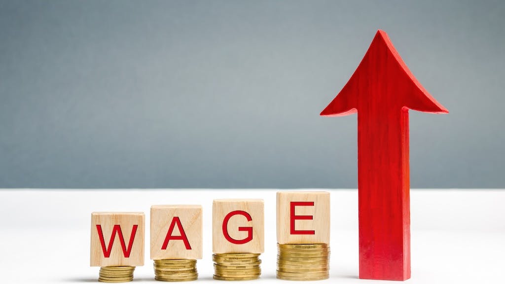 Wooden blocks with coins and the word 'wage' and an up arrow