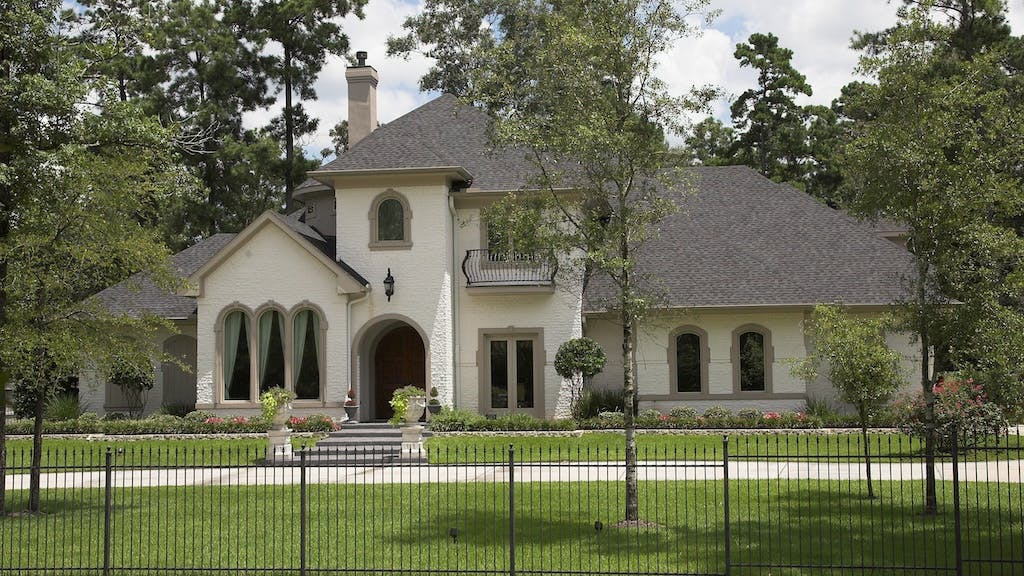 Exterior of gated luxury home surrounded by trees