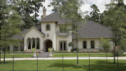 Exterior of gated luxury home surrounded by trees Exterior of gated luxury home surrounded by trees